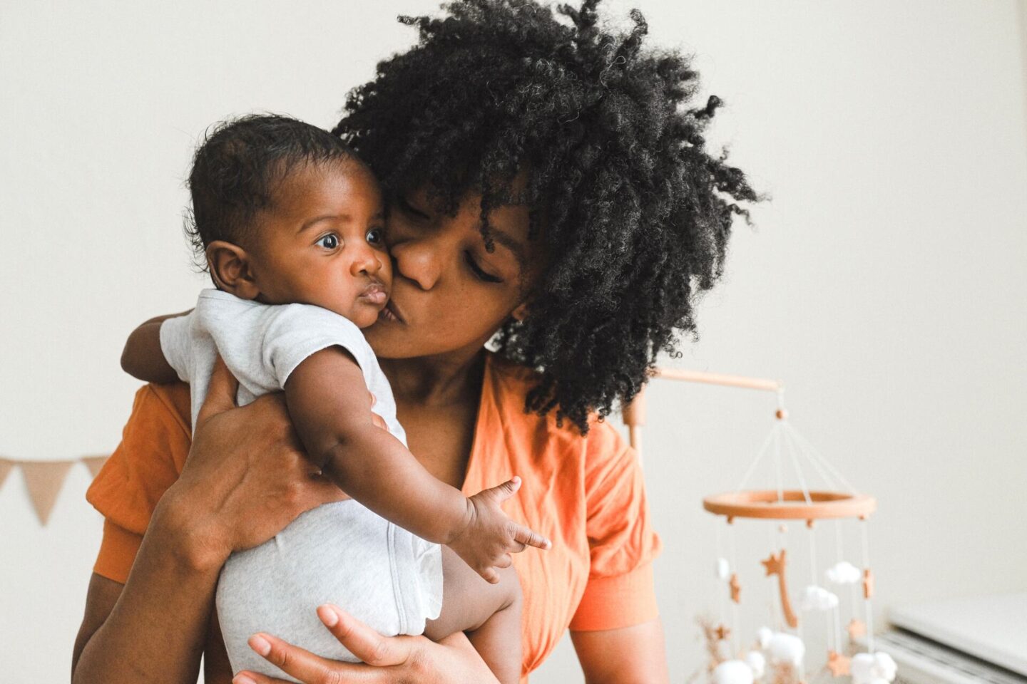 Last minute Mother's Day gift ideas for first time moms blog post banner - Black Mother kissing Black infant on cheek