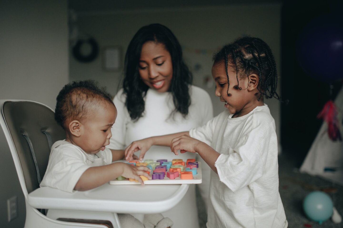 Mother helping her two sons complete an alphabet puzzle