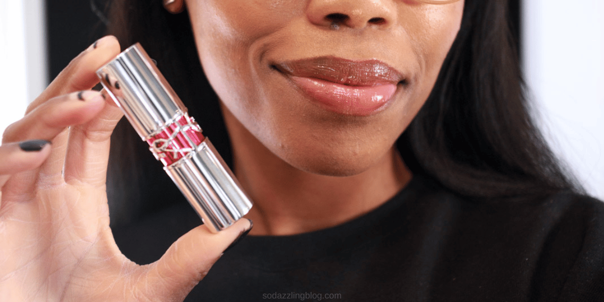 Black woman holding YSL Candy Glaze Lip Gloss Stick in shade flushing rosé